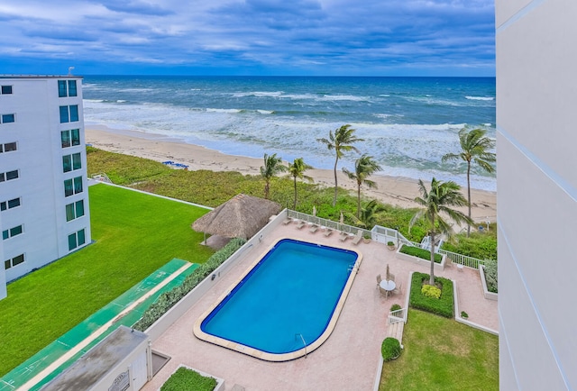 view of swimming pool featuring a water view, a yard, and a beach view