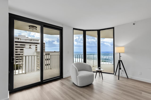 living area featuring expansive windows, a water view, and light wood-type flooring