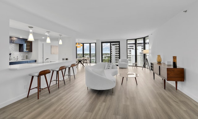 living room featuring floor to ceiling windows, sink, a chandelier, and light hardwood / wood-style floors