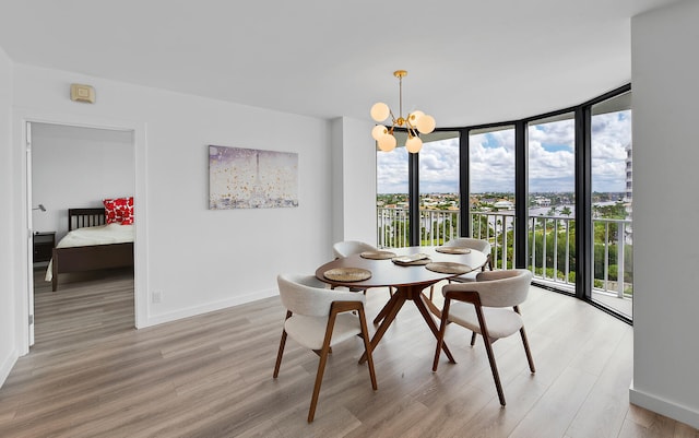 dining space featuring an inviting chandelier, a wall of windows, and light wood-type flooring