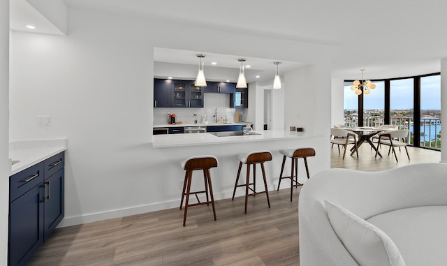 kitchen featuring pendant lighting, a breakfast bar area, backsplash, kitchen peninsula, and light wood-type flooring