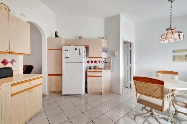 kitchen featuring backsplash, hanging light fixtures, white fridge, light tile patterned floors, and light brown cabinets