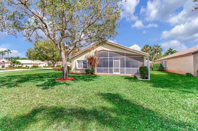 rear view of property featuring a sunroom and a lawn