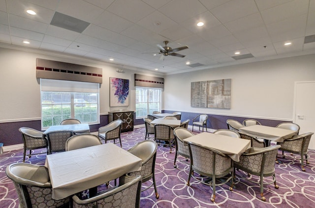 carpeted dining room with ornamental molding and ceiling fan