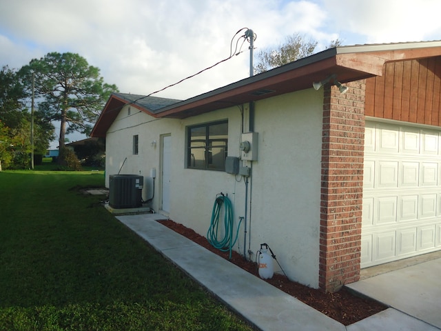 view of side of home with central AC unit, a lawn, and a garage