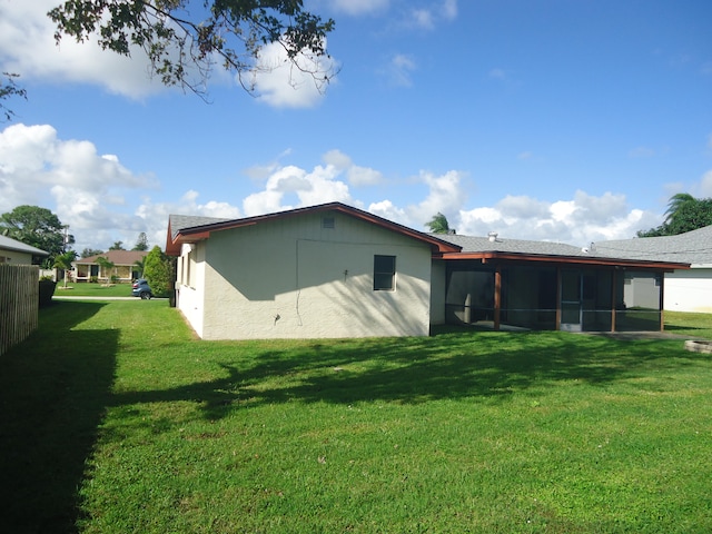 back of property with a sunroom and a yard