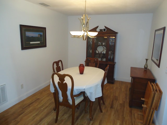 dining area with an inviting chandelier and dark hardwood / wood-style flooring