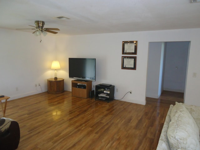 living room featuring dark wood-type flooring and ceiling fan