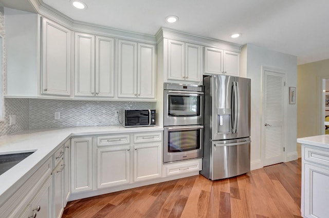 kitchen with light hardwood / wood-style flooring, white cabinetry, tasteful backsplash, and stainless steel appliances