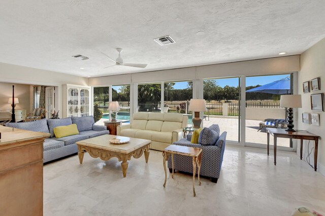 living room with a textured ceiling, a healthy amount of sunlight, and ceiling fan