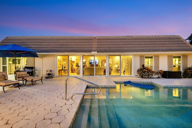 pool at dusk with a patio