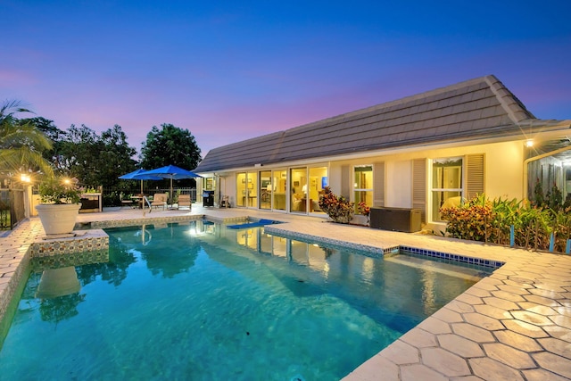 pool at dusk featuring a patio