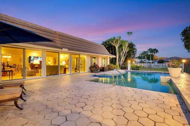 pool at dusk with a patio area