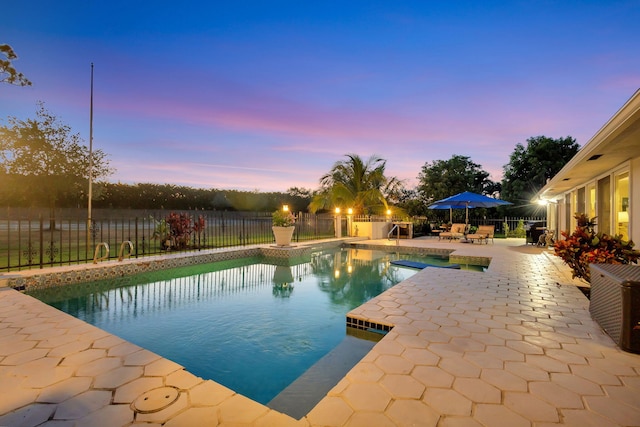 pool at dusk featuring a patio