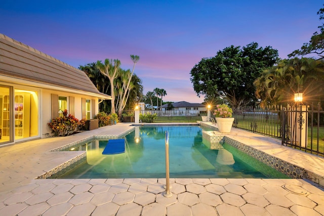 pool at dusk with a patio area