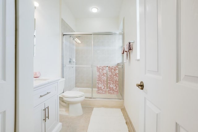 bathroom featuring toilet, a shower stall, vanity, and tile patterned floors