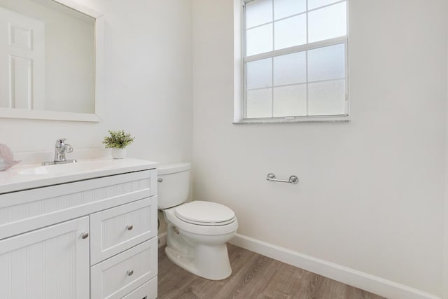 bathroom with toilet, baseboards, wood finished floors, and vanity