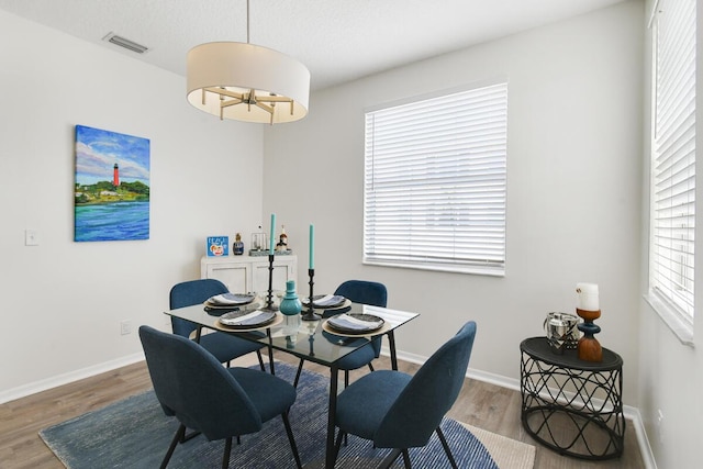 dining room featuring baseboards, visible vents, and wood finished floors