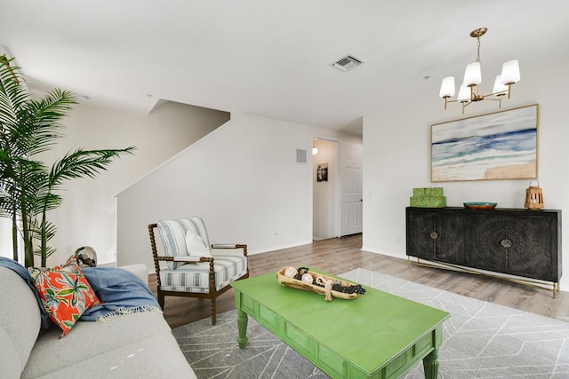 living room featuring visible vents, a notable chandelier, baseboards, and wood finished floors