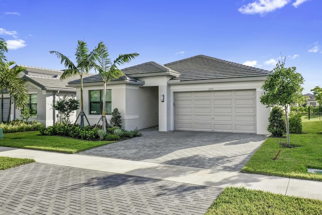 ranch-style house with a front lawn, stucco siding, an attached garage, and decorative driveway