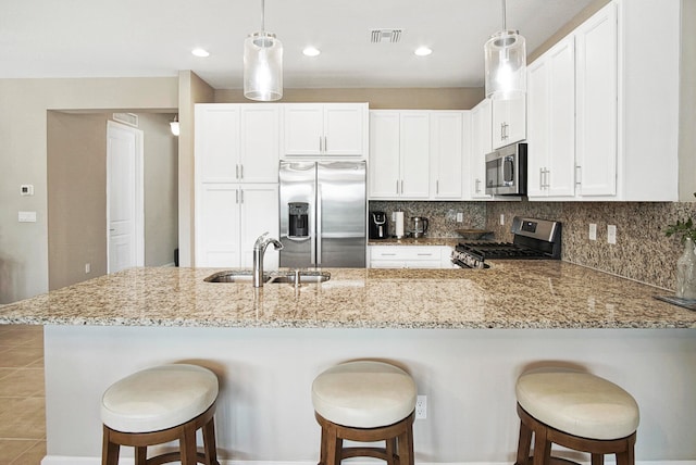 kitchen with a kitchen breakfast bar, kitchen peninsula, stainless steel appliances, sink, and white cabinetry