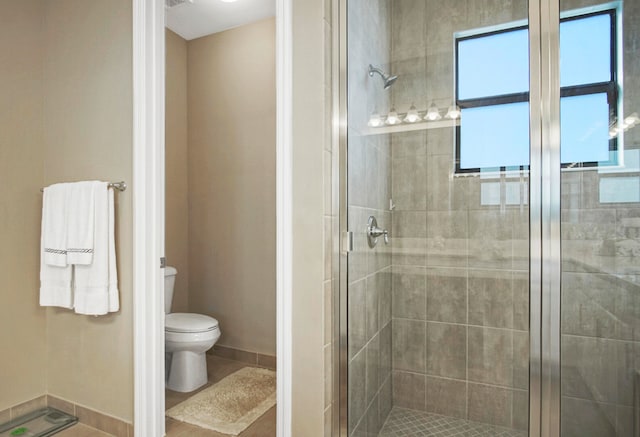 bathroom with a shower with door and toilet