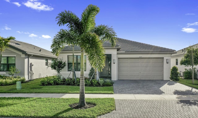 ranch-style home with decorative driveway, an attached garage, a front yard, and stucco siding