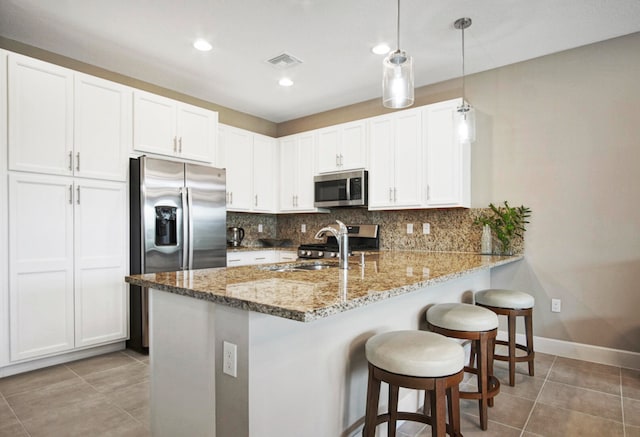 kitchen with kitchen peninsula, sink, pendant lighting, white cabinetry, and appliances with stainless steel finishes