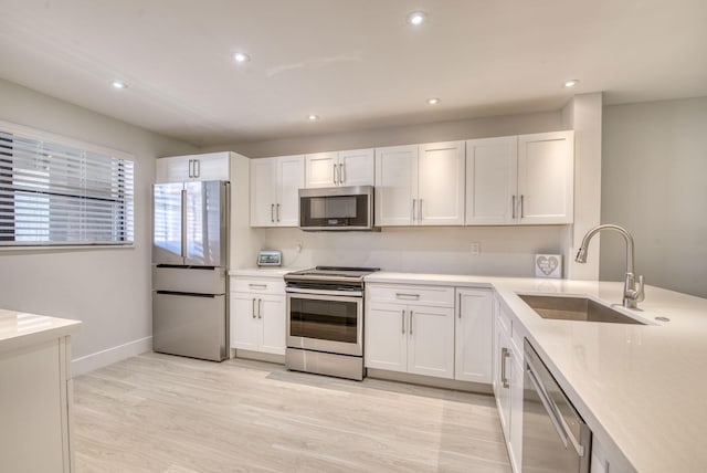 kitchen with white cabinetry, sink, light hardwood / wood-style floors, and appliances with stainless steel finishes