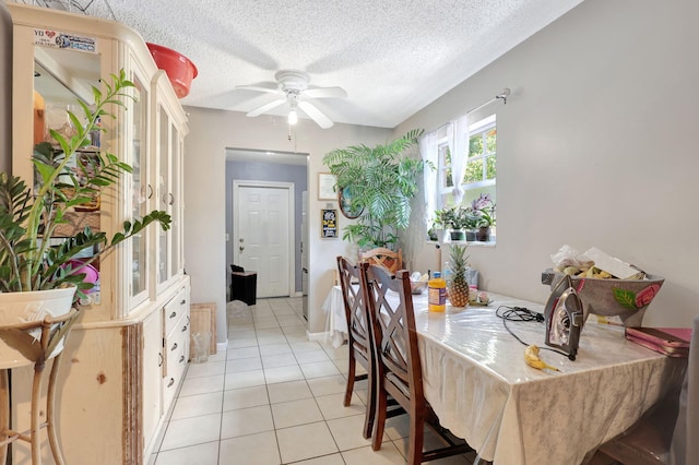 tiled dining room with a textured ceiling and ceiling fan