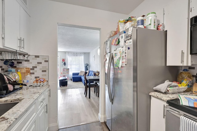 kitchen with white cabinets, stainless steel appliances, light hardwood / wood-style floors, and tasteful backsplash