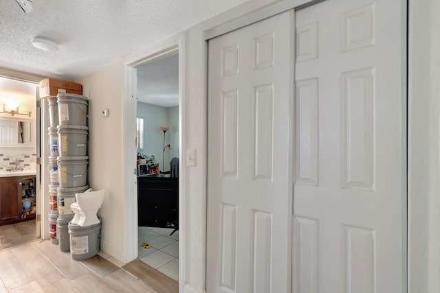 hallway featuring light hardwood / wood-style floors and a textured ceiling