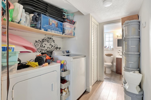 laundry area featuring a textured ceiling, light hardwood / wood-style flooring, and washing machine and dryer