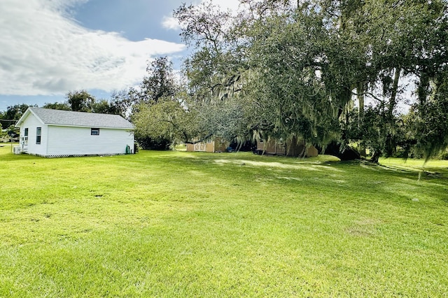 view of grassy yard with view of wooded area