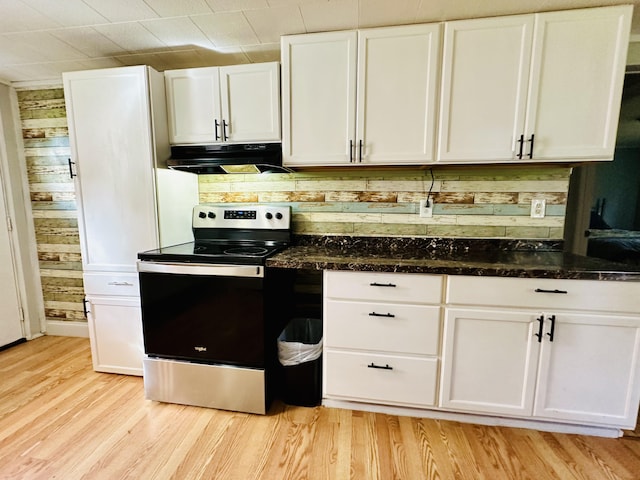 kitchen featuring dark stone countertops, range hood, stainless steel range with electric cooktop, light wood-type flooring, and white cabinetry