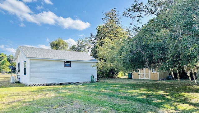 view of grassy yard featuring an outbuilding, a storage unit, and central AC