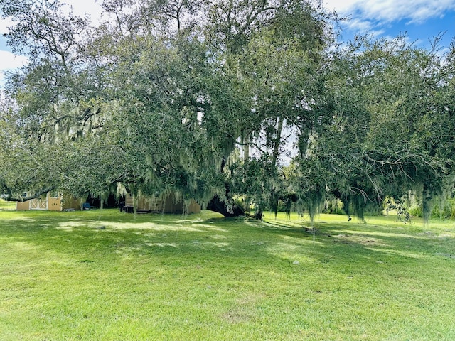 view of grassy yard featuring view of scattered trees, an outdoor structure, and a barn