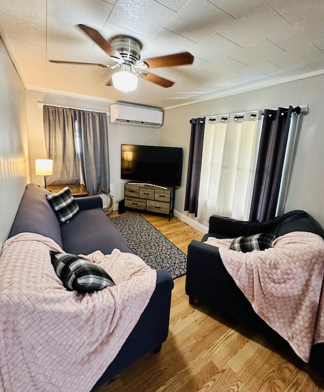 living area featuring a wall mounted AC, wood finished floors, a ceiling fan, and crown molding