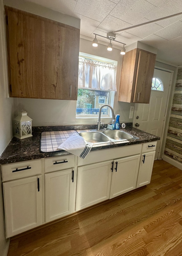kitchen with a sink, light wood-type flooring, plenty of natural light, and white cabinets