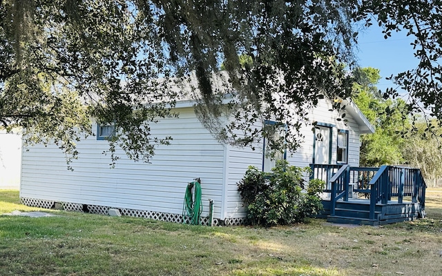 view of side of home with a yard, a wooden deck, and crawl space