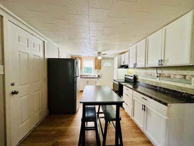 kitchen featuring stainless steel appliances, a sink, extractor fan, and white cabinets