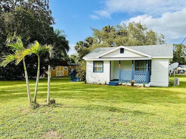 view of front facade featuring covered porch, a storage shed, and a front yard