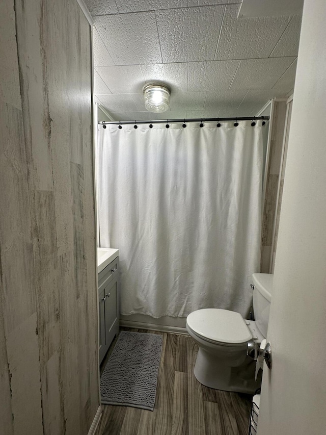 bathroom featuring toilet, vanity, wood finished floors, and shower / bathtub combination with curtain