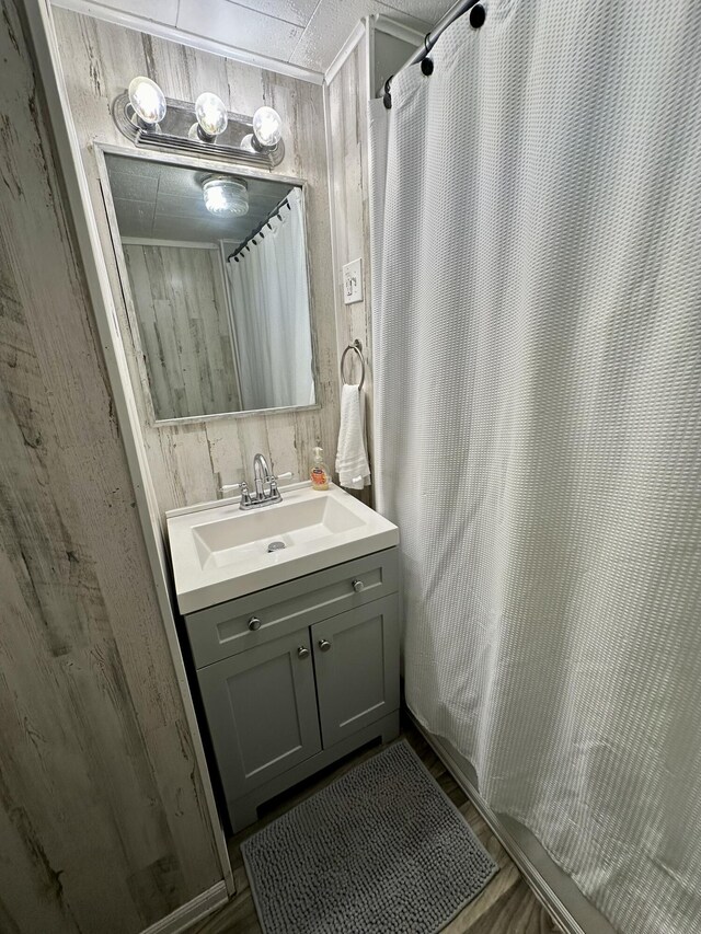 bathroom with vanity, wood finished floors, and wood walls