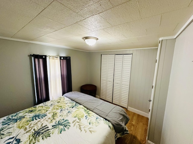 bedroom featuring wood finished floors, ornamental molding, and baseboards