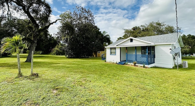 view of front facade with a porch, a front yard, and a shingled roof