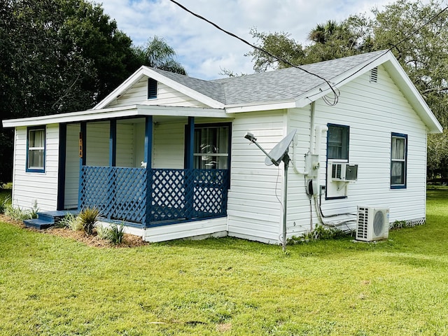 view of front facade featuring covered porch, ac unit, a front yard, a shingled roof, and cooling unit