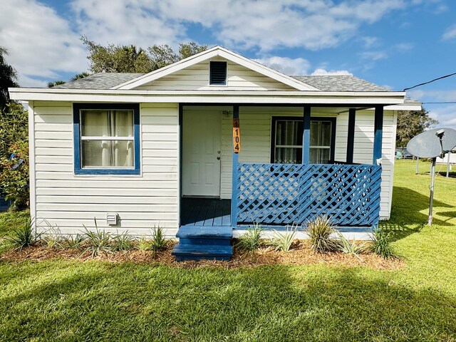 bungalow-style house featuring covered porch, roof with shingles, and a front lawn