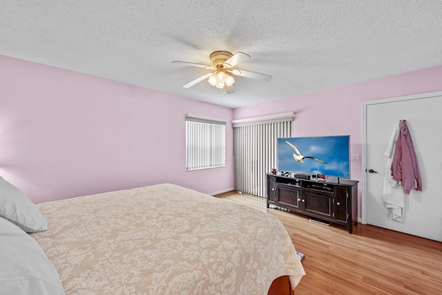 bedroom with a textured ceiling, light hardwood / wood-style flooring, and ceiling fan