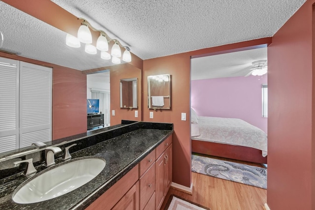 bathroom with vanity, hardwood / wood-style floors, a textured ceiling, and ceiling fan